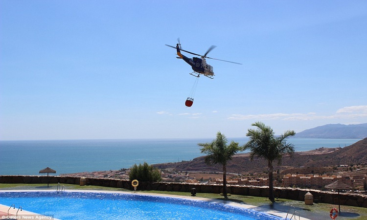 Ισπανία: Ελικόπτερο παίρνει νερό από πισίνα για να σβήσει φωτιά (Φώτο)